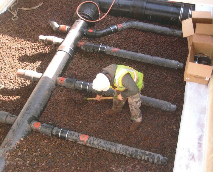 Flow-Strand lava rock being spread around the Sch 80 PVC air system. Perforated pipe is connected to the main trunk line via flex connectors.